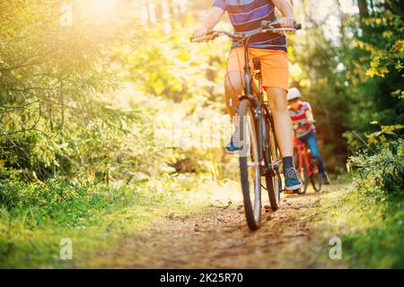 Kinder auf einem Fahrrad im Wald am frühen Morgen. Stockfoto