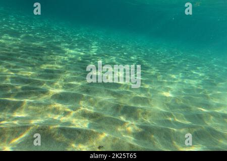 Meeresgrund in der Nähe von Sandstrand, Sonne leuchtet auf Sand 'dunes'. Unterwasser Foto, abstrakte marine Hintergrund. Stockfoto