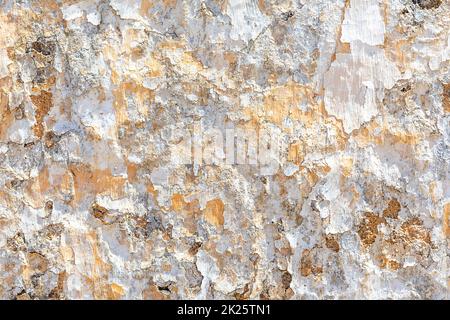 Hintergrund der alten Putzwand mit abblätternden Farben in Weiß und Orange Stockfoto