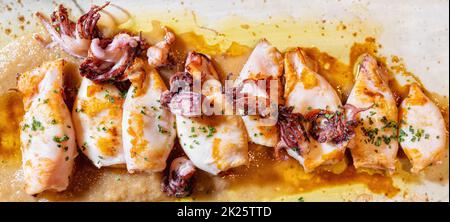 Direkt über dem Blick auf einen köstlichen Teller gegrillter Tintenfische mit Sauce. Stockfoto