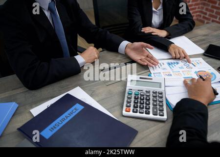 Geschäftstreffen am Schreibtisch bei der Arbeit. Menschliche Hände auf einem Tisch mit Ordner, Dokumenten, Grafiken, Diagrammen, Taschenrechner, Mobiltelefon und Tablet-Computer. Stockfoto