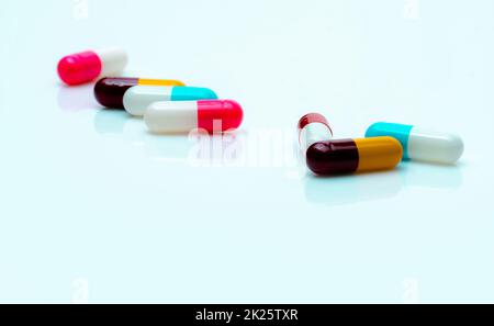 Mehrfarbige Antibiotikakapseln auf weißem Hintergrund. Antibiotikaresistenz. Antimikrobielle Kapselpillen. Pharmazeutische Industrie. Rosafarbene, weiße, blaue, gelbe und rote Kapseltabletten. Stockfoto