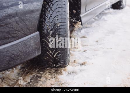 Auto mit Winterreifen auf einer schneebedeckten Straße, Winterwetter, rutschige Straße, gefahrvoll zu fahren, kalter Schneefall Stockfoto