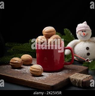 Gebackenes, nussförmiges Dessert in einem roten Keramikbecher, bestreut mit Puderzucker Stockfoto