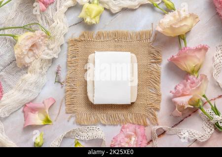 Seifenbügel auf Marmortisch neben rosa Blumen Stockfoto