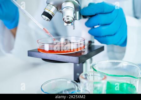 Asian Wissenschaftler Biochemiker oder Mikrobiologe arbeiten Forschung mit einem Mikroskop im Labor. Zum Schutz vor Ausbruch Coronavirus Covid19, Bakterien und Keimen. Stockfoto