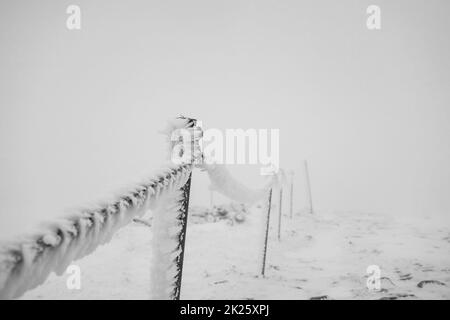 Kettenzäune bedeckt mit Eis und Schnee auf einem gefährlichen Abschnitt des Weges in den Bergen. Stockfoto