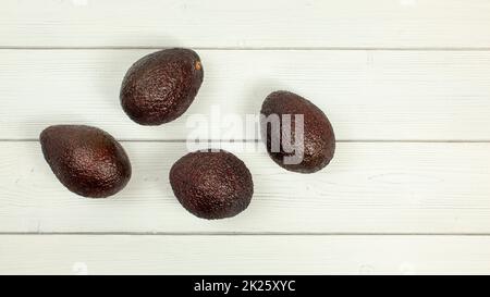 Vier reif braun Avocados auf White boards Schreibtisch. Tischplatte anzeigen. Stockfoto