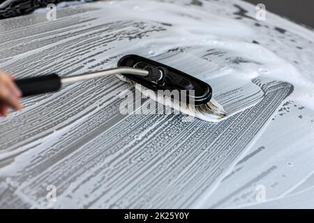 Bürste aus Anschläge in white Shampoo und Schaum auf dem Dach von Silver Auto in Waschstraße gewaschen dienen. Stockfoto