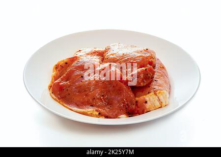 Schweinefleisch in Marinade liegt auf einem weißen Teller auf einem weißen isolierten Hintergrund Stockfoto