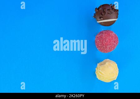 Sammlung von Schokoladenbonbons auf einem bunten Hintergrund. Schokoladenpralinen auf blauem Hintergrund mit Kopierfläche. Flach liegend, Draufsicht Stockfoto