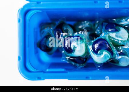 Waschpulver in mehrfarbigen Kapseln befinden sich in einer blauen Plastikbox. Das Konzept von Waschen und Sauberkeit. Stockfoto