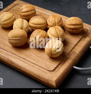 Gebackene Dessertnüsse mit Kondensmilch auf einem Holzbrett, Draufsicht Stockfoto