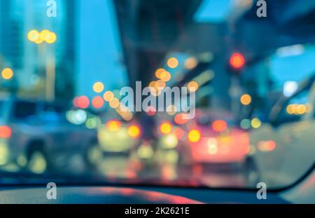 Verwischen Sie das Auto durch die Windschutzscheibe mit Bokeh-Lichtern in der Dämmerung Stockfoto