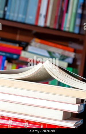 Bücher mit Bibliothek im Hintergrund gestapelt Stockfoto