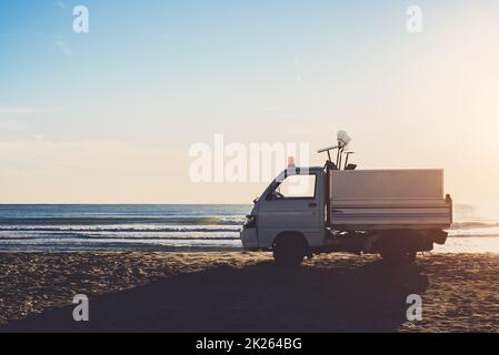 Auto der Reinigung am Strand bei Sonnenaufgang Stockfoto