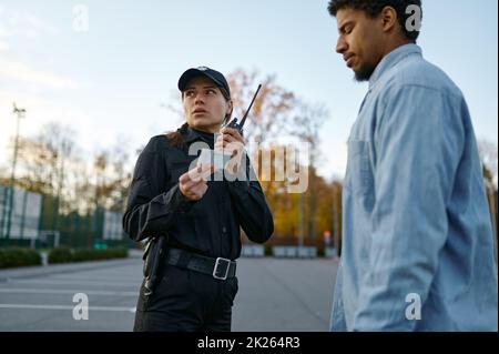 Weiblicher Polizist, der das Ausweisdokument der männlichen Passanten überprüft Stockfoto