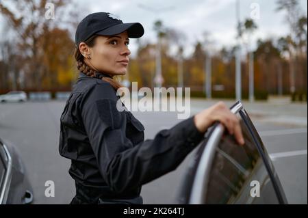 Polizeifrau in Uniform in der Nähe von Autoporträt Stockfoto