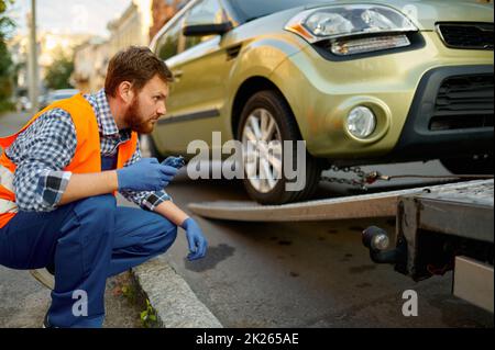 Männlicher Straßenarbeiter, der den Ladevorgang des Fahrzeugs überwacht Stockfoto