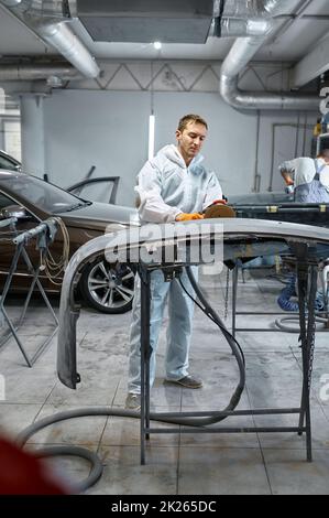 Militärangehöriger beim Polieren von Karosserieteilen in der Werkstatt Stockfoto