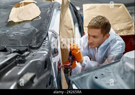 Reparaturman hält Drehpolierer für die Kitt-Korrektur Stockfoto