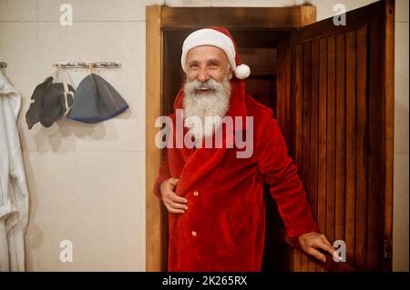 Fröhlicher, entspannter Weihnachtsmann, der aus der Dampfsauna kommt Stockfoto