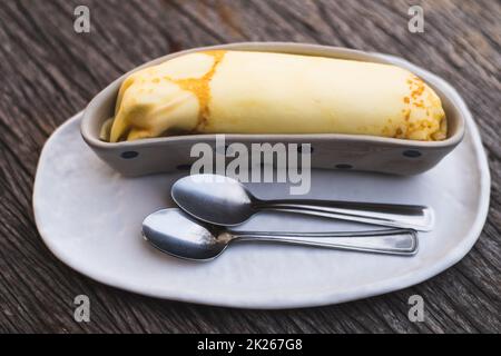 Banana Crepe süß Dessert Objekt Stillleben. Die Kreppe in die Keramik-Behälter Schüssel Bananenform Form Design. Stockfoto