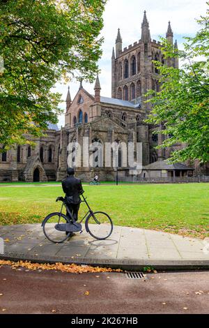 Bronzeskulptur von Sir Edward Elgar mit seinem Fahrrad von Jemma Pearson vor der Kathedrale in Hereford, Herefordshire, England, Großbritannien Stockfoto