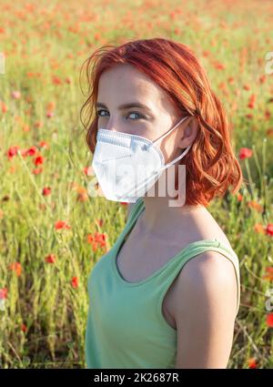 Junges Mädchen mit Schutzmaske in Mohn Feld Stockfoto