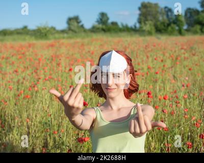 Frustriertes junges Mädchen mit Schutzmaske im Mohnfeld Stockfoto