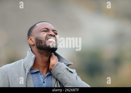 Ein Mann mit schwarzer Haut leidet im Winter an Nackenschmerzen Stockfoto