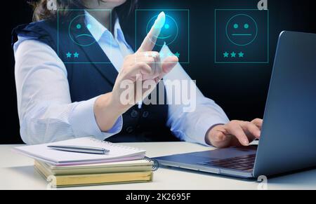 Eine Frau sitzt und arbeitet an einem Laptop, Qualitätsbewertung und Bewertung von Produkten, Website. Kundenbewertungen Stockfoto