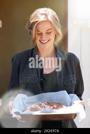 Das Leben ist besser mit frisch gebackenem Brot. Eine junge Frau mit einem frisch gebackenen Brot. Stockfoto