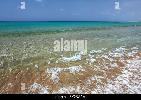 Kristallklares Wasser mit kleinen Wellen, azurblaues Meer im Hintergrund. Unberührte leer wilden Strand in Karpass Halbinsel, Nordzypern Stockfoto