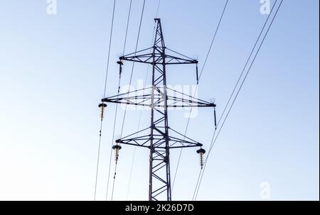 Hochspannungsleitungen, Pfosten oder Turm vor dem Hintergrund eines schönen Himmels. Sequenziell bestellte Hochenergie-Pylone. Stockfoto