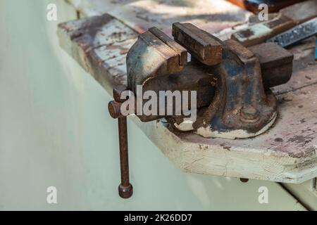 Ein alter Schraubstock auf einer Werkbank Stockfoto
