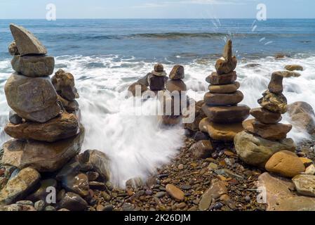 Pyramiden von Meeressteinen an der Küste.Eingang zum Meer. Stockfoto