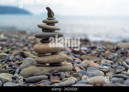 Eine Pyramide aus Seesteinen im Hintergrund des Meeres. Stockfoto