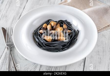 Schwarze Pasta mit Babypilzen Stockfoto