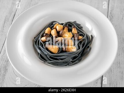 Schwarze Pasta mit Babypilzen Stockfoto