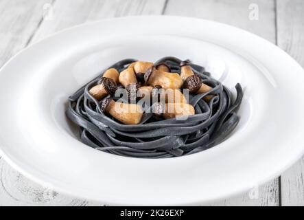 Schwarze Pasta mit Babypilzen Stockfoto