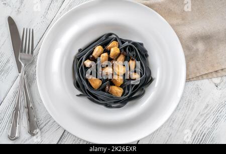 Schwarze Pasta mit Babypilzen Stockfoto