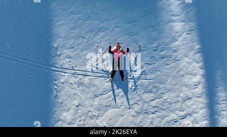 Luftaufnahme mit einer Drohne von einer Frau mit Langlaufskiern im Schnee. Wintersport für Senioren Stockfoto