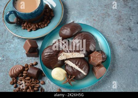 Zefir (zephyr), Kaffeetasse, Bohnen, Schokolade auf Küchentisch, Auswahl an dunklen, weißen und milchigen Schokoladenbonbons. Stockfoto