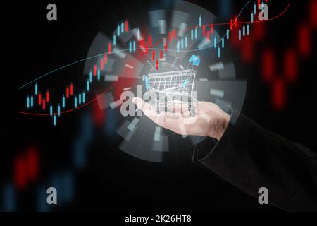 Die Hand eines Mannes hält einen Miniatur-Einkaufswagen auf dunkelblauem Hintergrund, das Konzept des Beginns des weltweiten Verkaufs, das Wachstum der Käufe. Online-Shopping Stockfoto