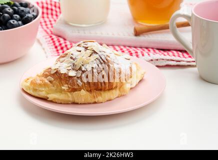 Gebackene Croissants mit Puderzucker bestreut, Heidelbeeren auf einem weißen Tisch, Frühstück Stockfoto