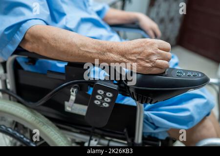 Asian senior or elderly old lady woman patient on electric wheelchair with remote control at nursing hospital ward, healthy strong medical concept Stock Photo