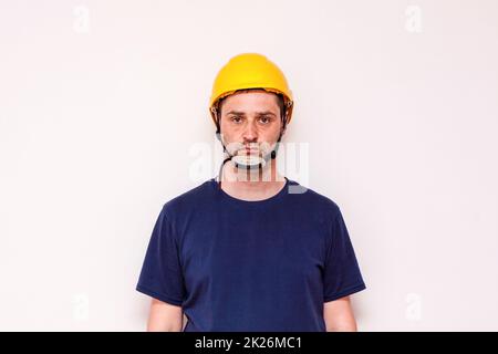 Bauarbeiter hinter weißem Hintergrund. Trägt eine grüne Maske und einen gelben Helm Stockfoto