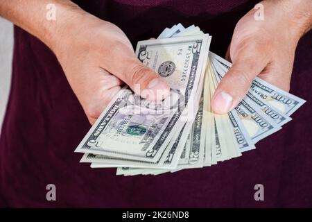 Der Mann hält einen Haufen Dollar in der Hand. US-Dollar Stockfoto