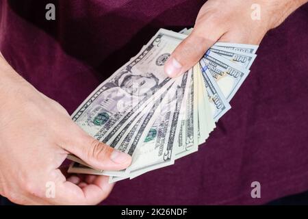 Der Mann hält einen Haufen Dollar in der Hand. US-Dollar Stockfoto